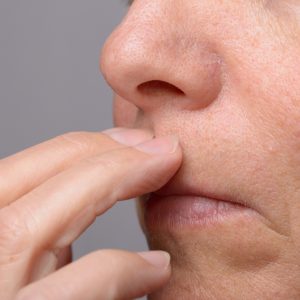 Klopfen mit den Fingern auf einen Punkt zwischen Nase und Lippen